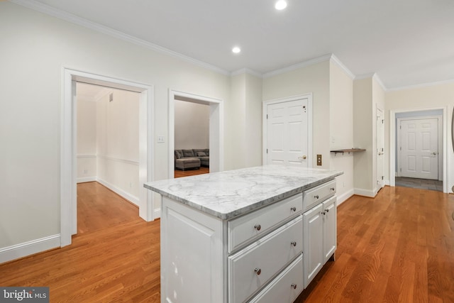 kitchen featuring crown molding, light hardwood / wood-style flooring, light stone counters, and a kitchen island