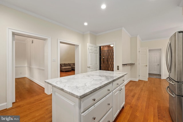 kitchen with white cabinets, stainless steel refrigerator, light hardwood / wood-style flooring, crown molding, and light stone counters