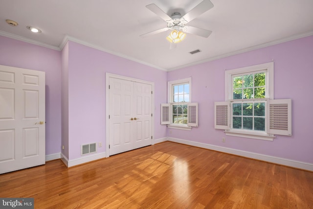 unfurnished bedroom with a closet, light hardwood / wood-style flooring, ceiling fan, and crown molding