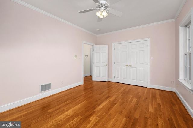 unfurnished bedroom with ornamental molding, wood-type flooring, a closet, and ceiling fan