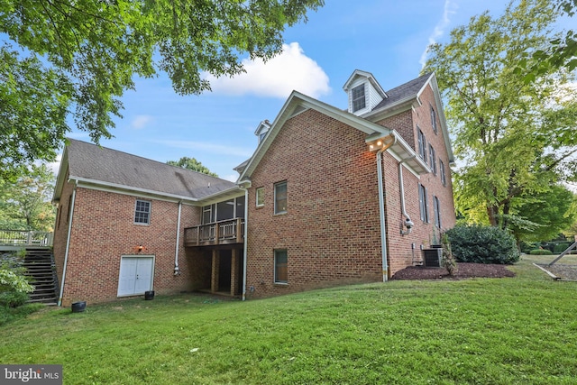 rear view of property featuring a deck, central AC unit, and a lawn