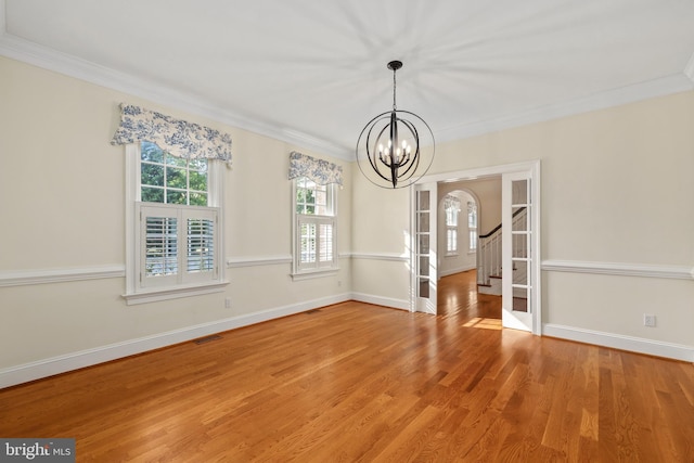 unfurnished dining area featuring a notable chandelier, ornamental molding, and hardwood / wood-style flooring