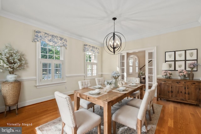 dining area with a notable chandelier, ornamental molding, and hardwood / wood-style flooring