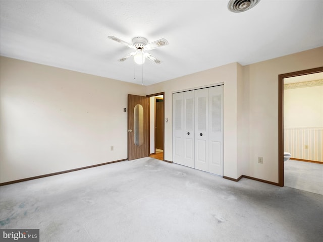 unfurnished bedroom featuring light carpet, connected bathroom, a closet, and ceiling fan