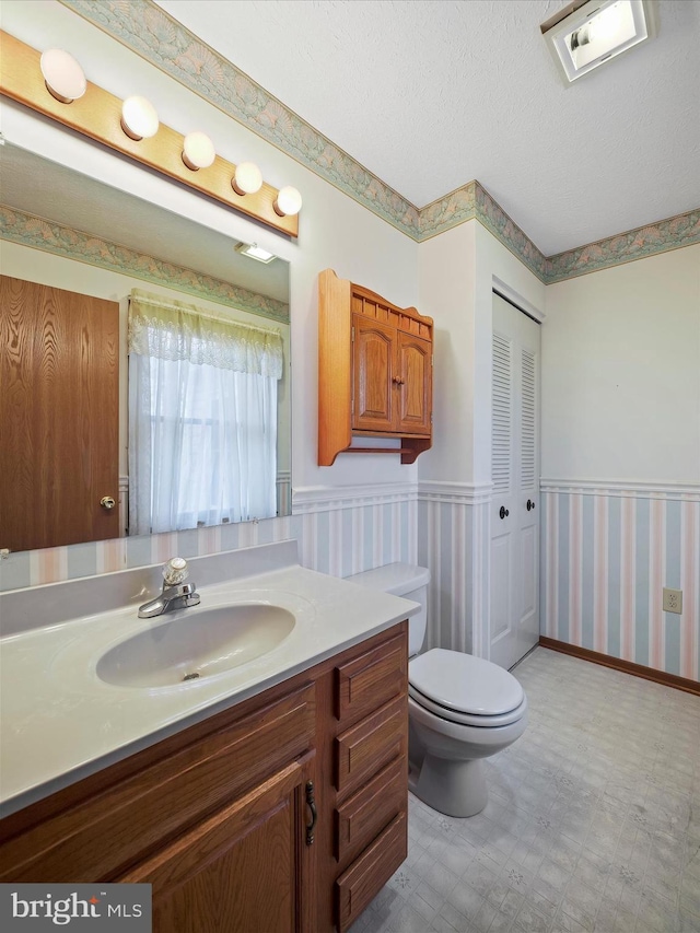 bathroom with vanity, toilet, and a textured ceiling