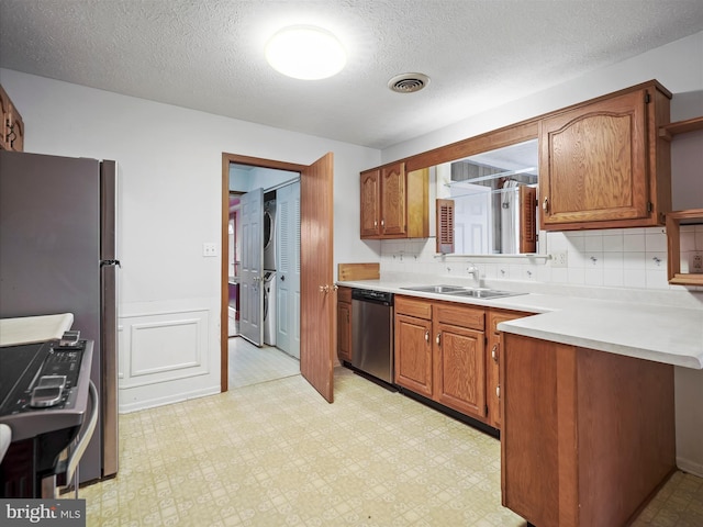 kitchen featuring washer / dryer, sink, a textured ceiling, appliances with stainless steel finishes, and backsplash