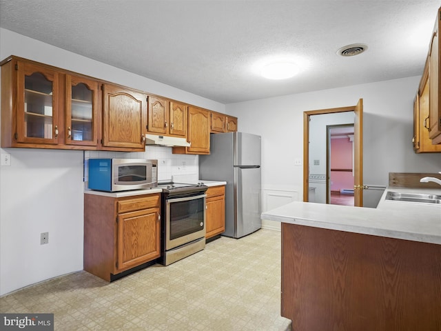 kitchen featuring sink, backsplash, a textured ceiling, and appliances with stainless steel finishes