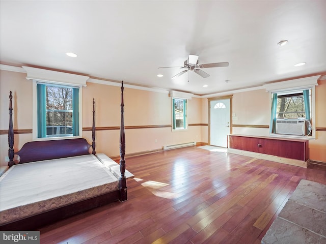 unfurnished bedroom featuring multiple windows, a baseboard heating unit, hardwood / wood-style flooring, and ornamental molding