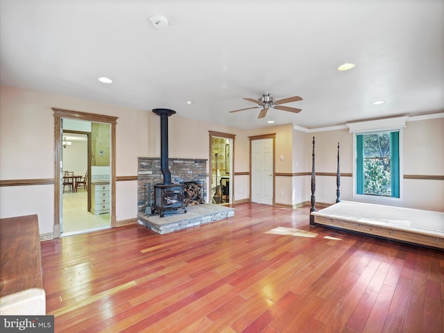 unfurnished living room featuring light hardwood / wood-style floors, ceiling fan, and a wood stove