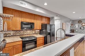 kitchen featuring light countertops, brown cabinets, black appliances, backsplash, and visible vents