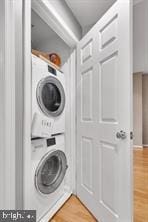 clothes washing area featuring stacked washer / dryer and hardwood / wood-style floors