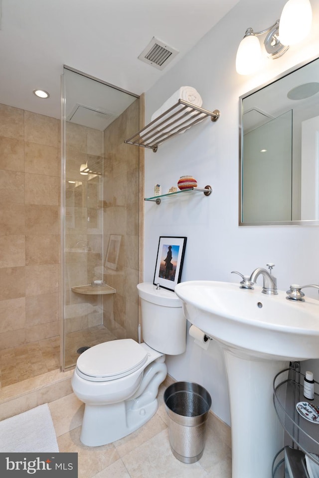 bathroom with tiled shower, sink, toilet, and tile patterned flooring