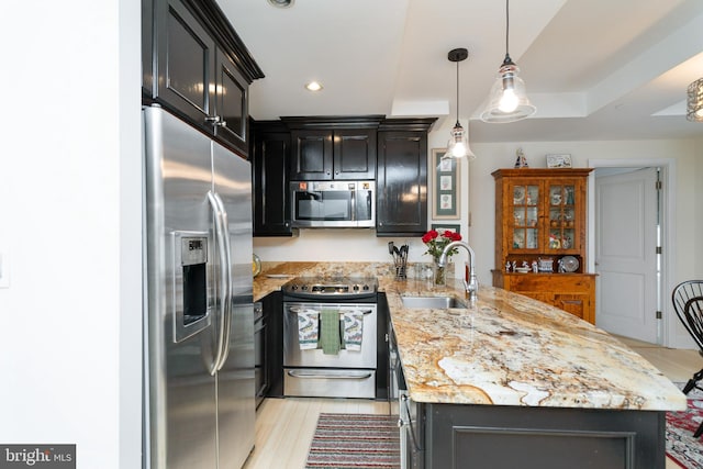 kitchen featuring light hardwood / wood-style flooring, sink, light stone countertops, pendant lighting, and appliances with stainless steel finishes