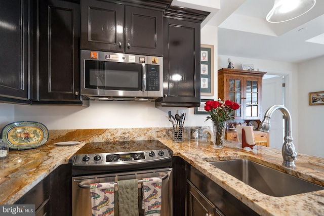 kitchen featuring light stone countertops, stainless steel appliances, and sink