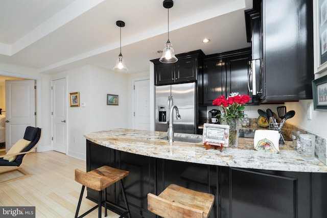 kitchen featuring light hardwood / wood-style floors, decorative light fixtures, light stone counters, and stainless steel refrigerator with ice dispenser