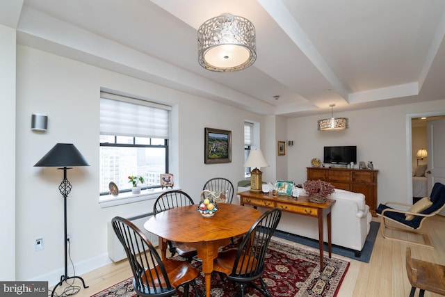 dining area featuring a tray ceiling and light wood-type flooring