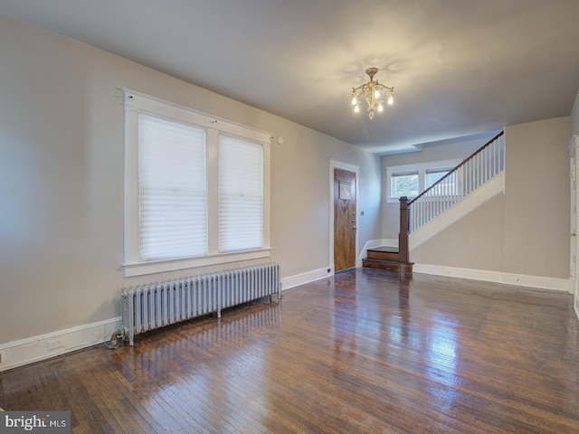 spare room featuring radiator heating unit, a notable chandelier, and dark hardwood / wood-style flooring