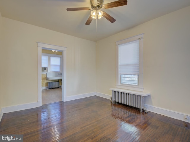 empty room with dark hardwood / wood-style flooring, radiator heating unit, and a healthy amount of sunlight