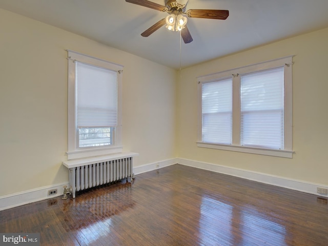 empty room with ceiling fan, dark hardwood / wood-style floors, and radiator heating unit