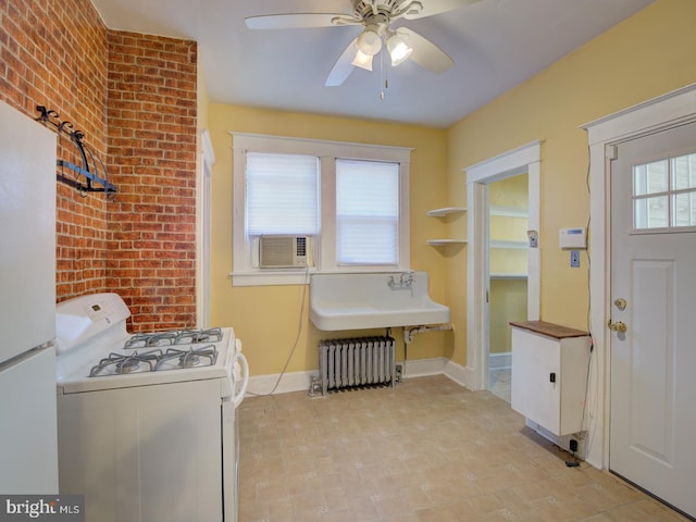 clothes washing area with radiator heating unit, cooling unit, sink, ceiling fan, and brick wall