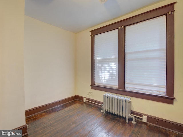 spare room featuring dark wood-type flooring and radiator