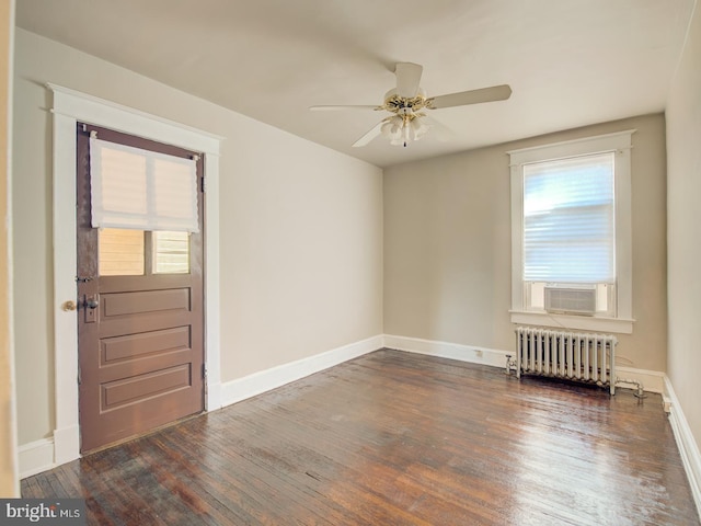 spare room featuring radiator, ceiling fan, plenty of natural light, and dark hardwood / wood-style flooring