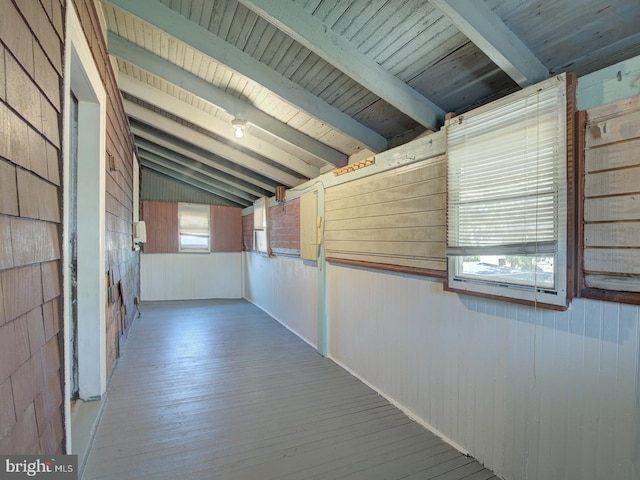 hall featuring lofted ceiling with beams, wood walls, wooden ceiling, and wood-type flooring