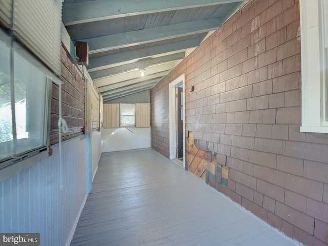 hall featuring lofted ceiling with beams, light hardwood / wood-style flooring, and wooden walls