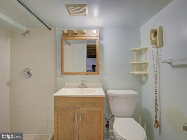 bathroom with a tile shower, vanity, and toilet