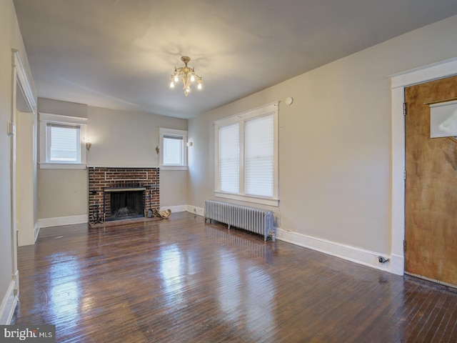 unfurnished living room featuring dark wood-type flooring, radiator, a chandelier, and a healthy amount of sunlight