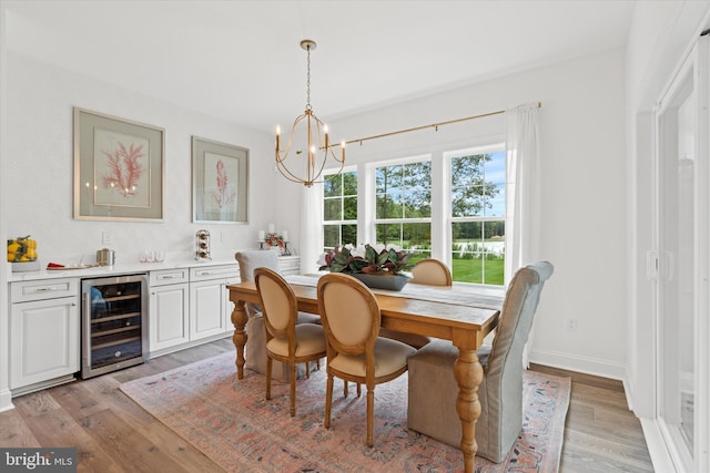 dining space featuring wine cooler, a notable chandelier, and light wood-type flooring