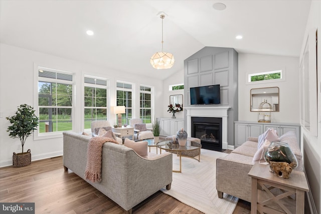 living room featuring wood-type flooring, a fireplace, and vaulted ceiling