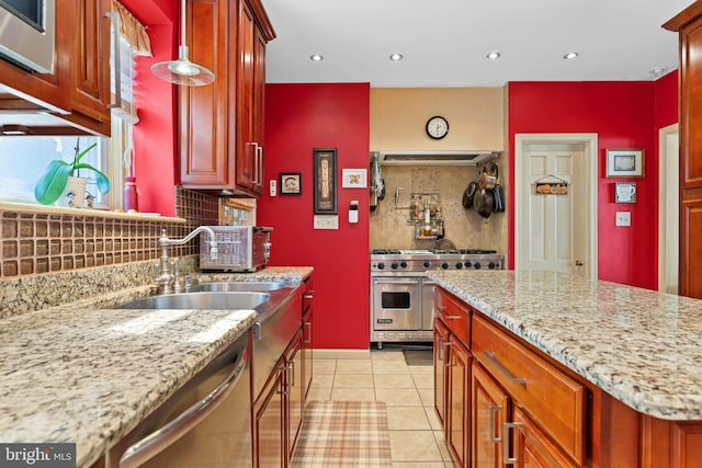 kitchen with appliances with stainless steel finishes, light stone counters, backsplash, and light tile patterned flooring