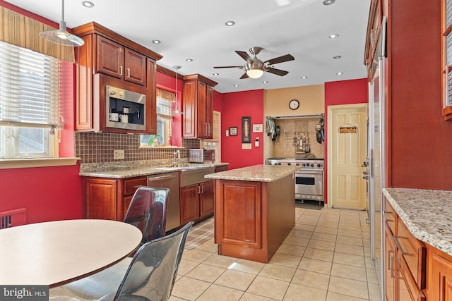 kitchen featuring light tile patterned floors, stainless steel appliances, decorative light fixtures, and a kitchen island