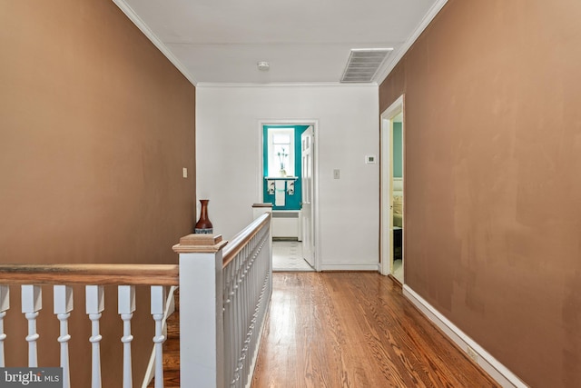 corridor with ornamental molding and hardwood / wood-style flooring