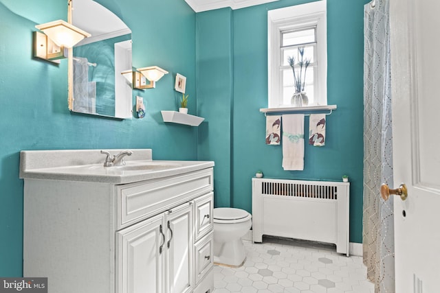 bathroom with toilet, tile patterned flooring, radiator, crown molding, and vanity