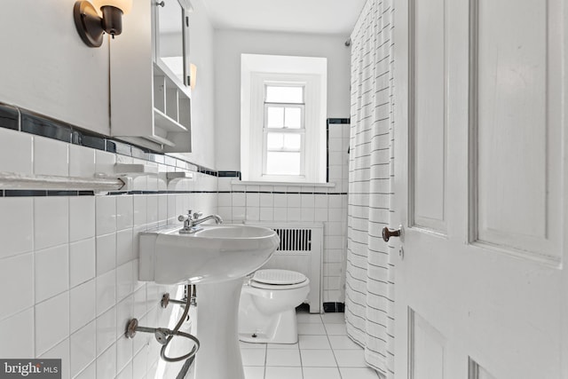 bathroom with toilet, tile walls, and tile patterned flooring