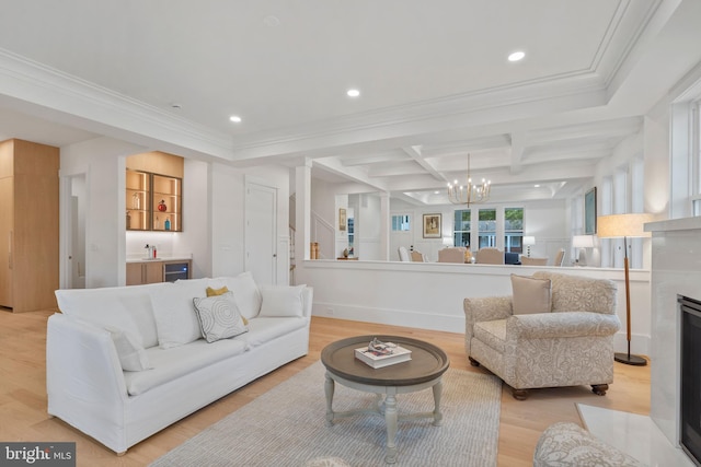 living room with coffered ceiling, beam ceiling, ornamental molding, light wood-type flooring, and a chandelier