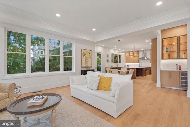 living area with visible vents, wine cooler, light wood-style floors, and crown molding