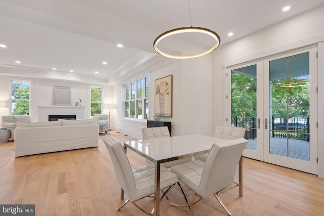 dining room featuring french doors, a fireplace, light wood-type flooring, and crown molding