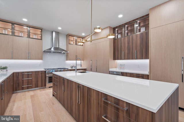 kitchen featuring glass insert cabinets, stainless steel stove, modern cabinets, wall chimney exhaust hood, and a sink