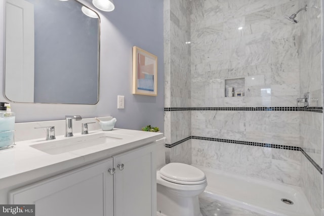 bathroom featuring toilet, vanity, and a tile shower