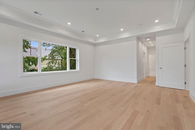 empty room with visible vents, a tray ceiling, recessed lighting, ornamental molding, and light wood-style floors