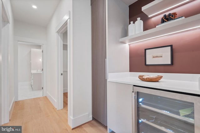 bar with wine cooler, a dry bar, recessed lighting, and light wood finished floors