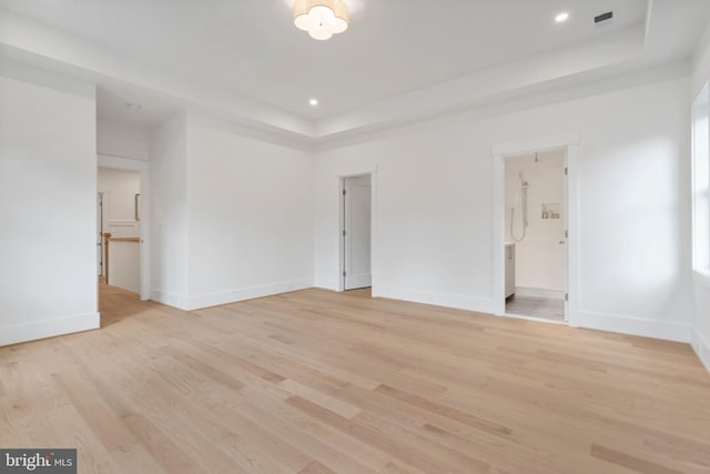 spare room with baseboards, visible vents, light wood finished floors, recessed lighting, and a raised ceiling