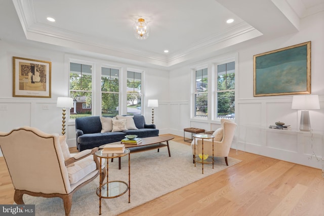 living room featuring crown molding, a tray ceiling, and light wood-type flooring