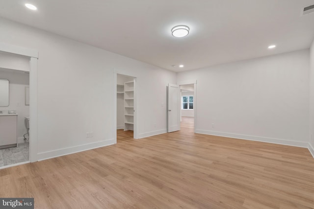 empty room featuring light wood-type flooring and stacked washing maching and dryer