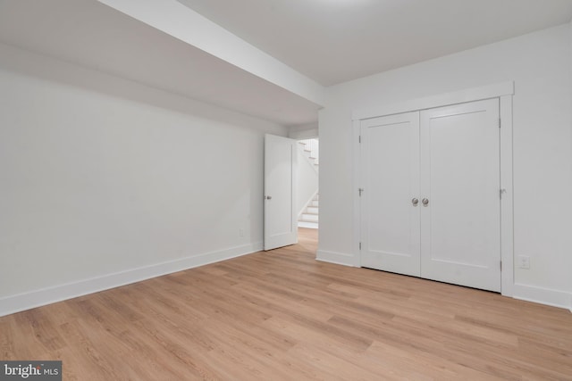 unfurnished bedroom featuring a closet, light wood-style flooring, and baseboards