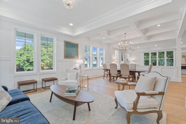 living room featuring beam ceiling, a decorative wall, light wood-style flooring, and an inviting chandelier