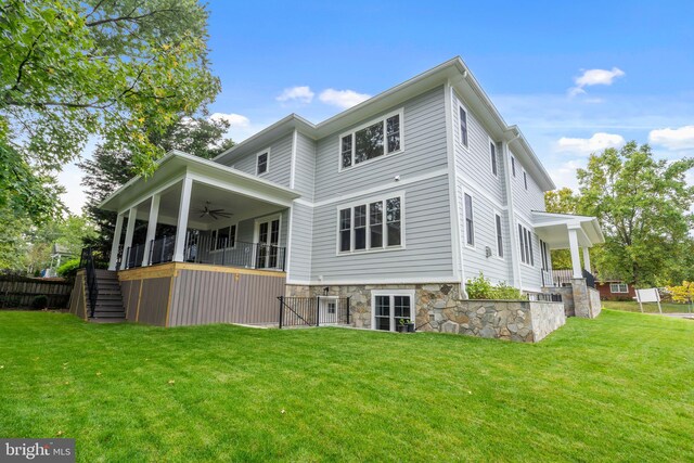 rear view of house featuring stairway, stone siding, a yard, and ceiling fan